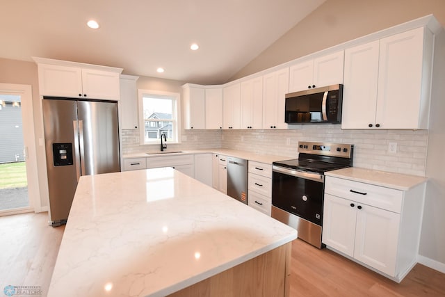 kitchen with appliances with stainless steel finishes, a sink, light wood-type flooring, tasteful backsplash, and white cabinetry