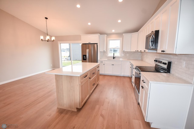 kitchen with stainless steel appliances, a sink, tasteful backsplash, light wood-style flooring, and a center island