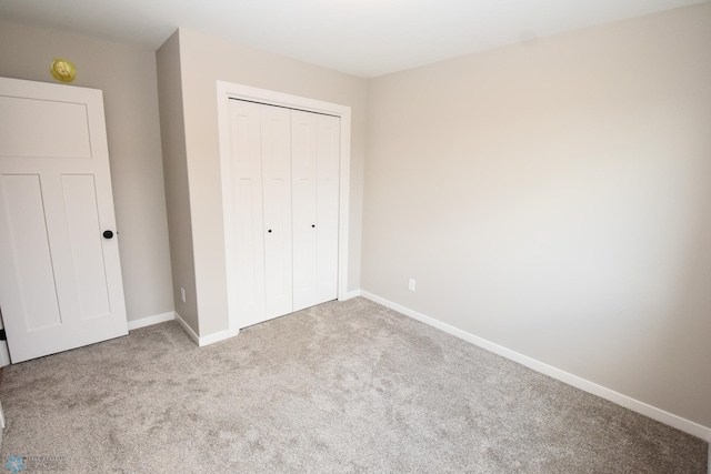 unfurnished bedroom with carpet, a closet, and baseboards