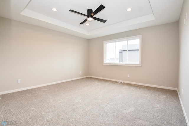 carpeted empty room featuring a raised ceiling, recessed lighting, ceiling fan, and baseboards