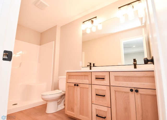 bathroom featuring toilet, wood finished floors, a shower, and double vanity