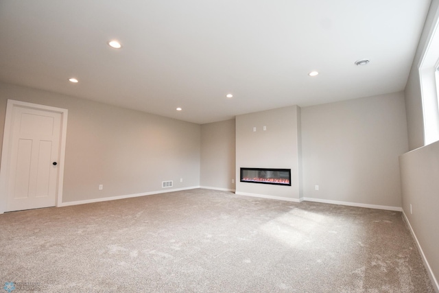 unfurnished living room with carpet, recessed lighting, a glass covered fireplace, and baseboards