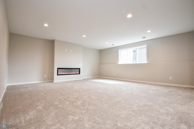 unfurnished living room with light colored carpet, baseboards, a glass covered fireplace, and recessed lighting