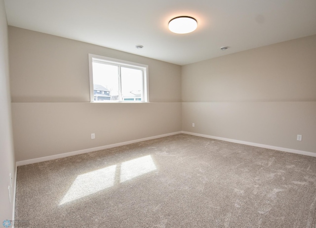 spare room featuring carpet and baseboards