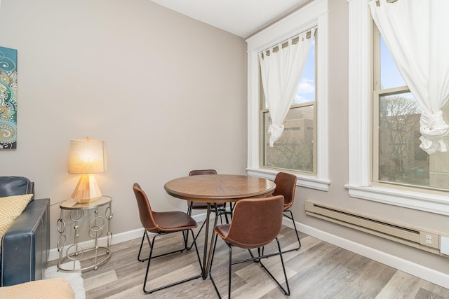 dining room featuring a baseboard radiator, wood finished floors, and baseboards