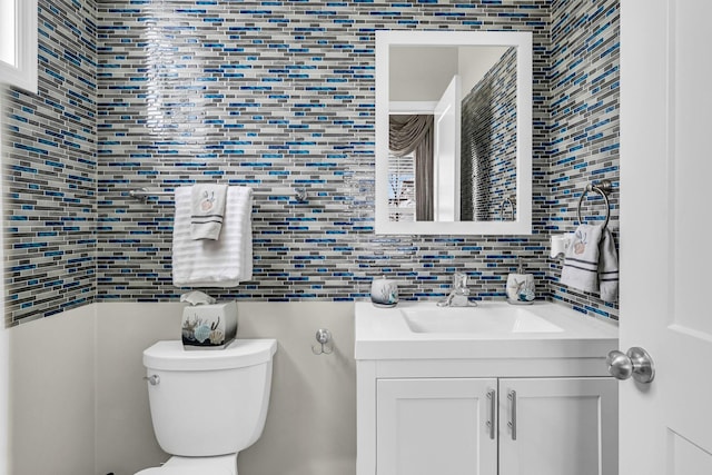 bathroom featuring tile walls, toilet, vanity, and decorative backsplash