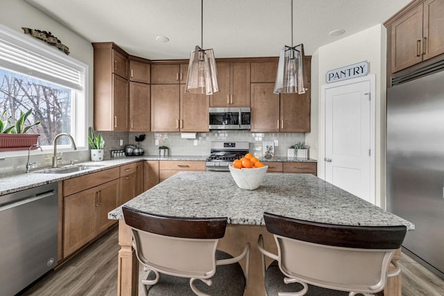 kitchen with backsplash, light wood-style flooring, stainless steel appliances, and a sink