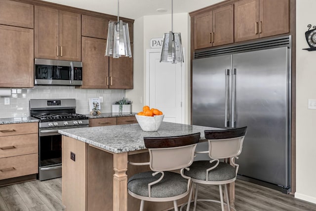 kitchen featuring decorative backsplash, appliances with stainless steel finishes, and light wood finished floors