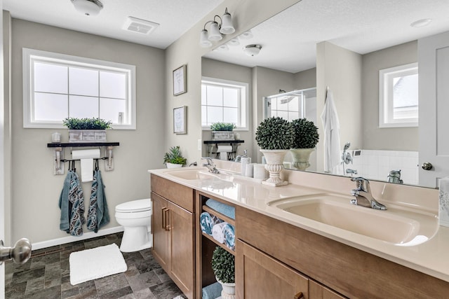 bathroom featuring visible vents, toilet, a stall shower, and a sink