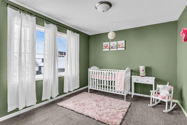 carpeted bedroom featuring a nursery area, baseboards, and a textured ceiling