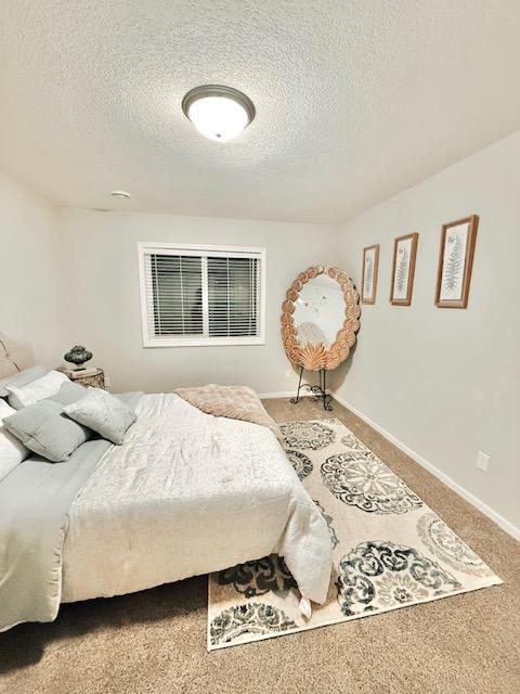 bedroom with carpet, a textured ceiling, and baseboards