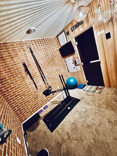 workout room with lofted ceiling and wooden walls