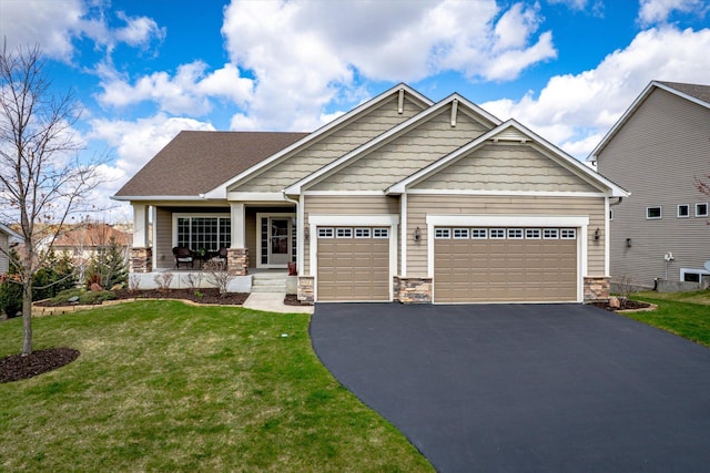 craftsman-style home with an attached garage, driveway, covered porch, stone siding, and a front yard