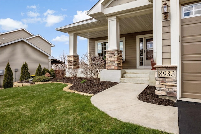 property entrance with stone siding, a lawn, and covered porch