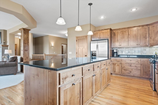 kitchen with dark countertops, a center island, light wood-style floors, and appliances with stainless steel finishes