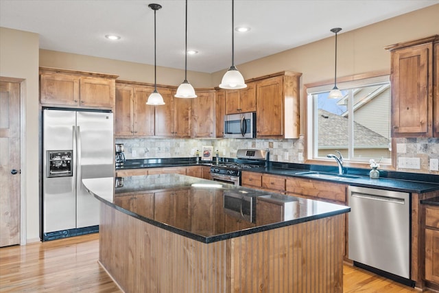 kitchen with a center island, tasteful backsplash, a sink, light wood finished floors, and appliances with stainless steel finishes