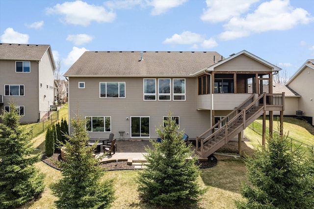 back of property with a lawn, a sunroom, a patio area, and stairs