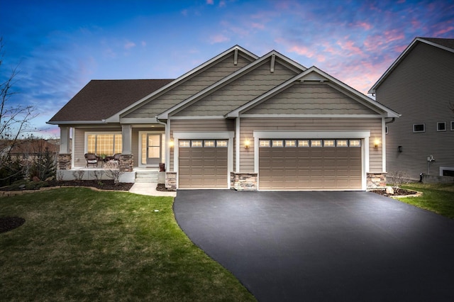 craftsman inspired home featuring a yard, driveway, stone siding, a porch, and a garage