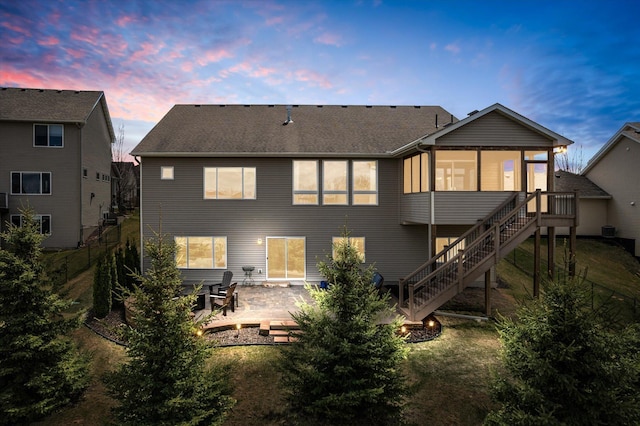 rear view of property featuring a yard, a sunroom, a patio area, and stairs