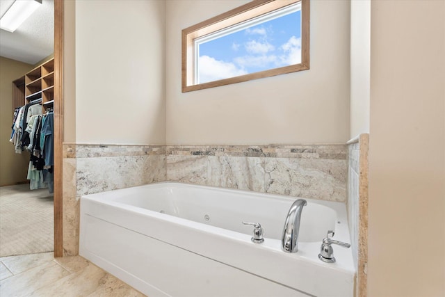 full bath featuring a spacious closet and a jetted tub