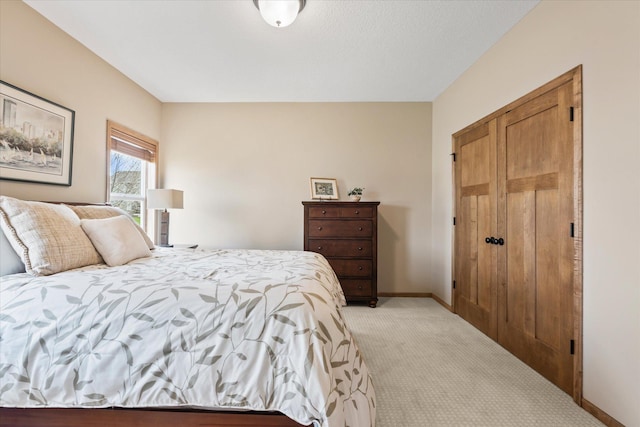 bedroom with baseboards and light colored carpet