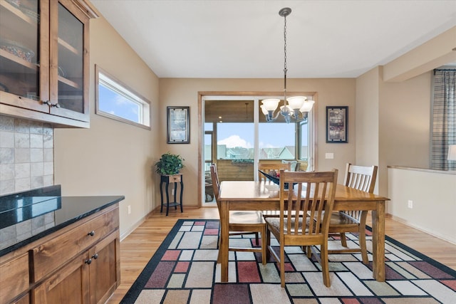 dining room featuring baseboards, a chandelier, and light wood finished floors