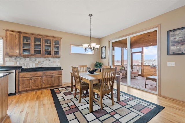 dining area with light wood-style flooring, baseboards, and an inviting chandelier