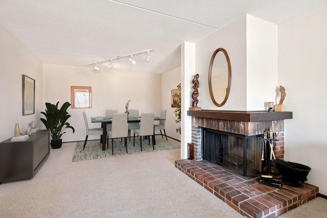 carpeted living area with track lighting and a brick fireplace