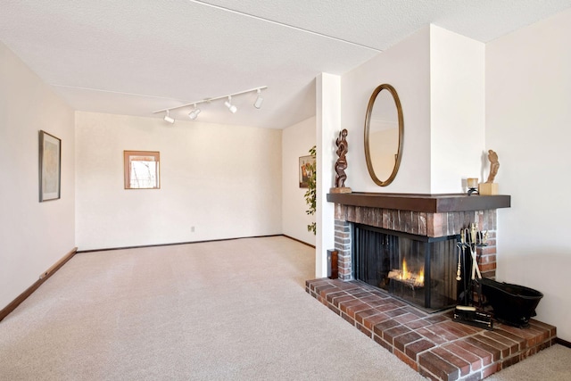 living room featuring baseboards, a brick fireplace, carpet flooring, and rail lighting