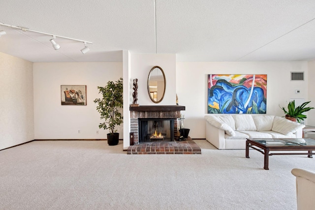 carpeted living room featuring track lighting, baseboards, visible vents, and a fireplace