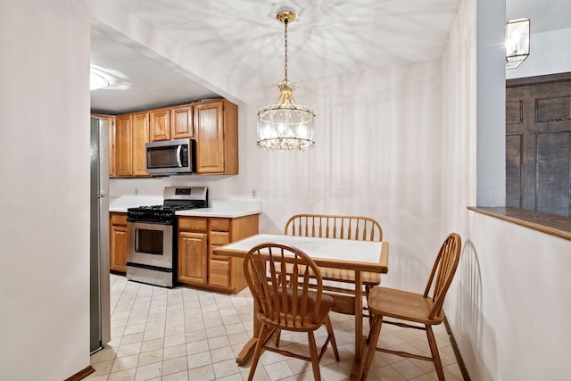 kitchen with light countertops, light tile patterned floors, decorative light fixtures, a chandelier, and appliances with stainless steel finishes