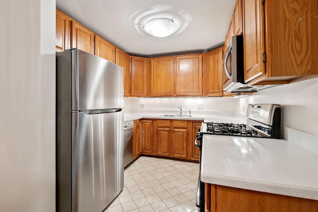 kitchen with light tile patterned flooring, appliances with stainless steel finishes, brown cabinets, and a sink