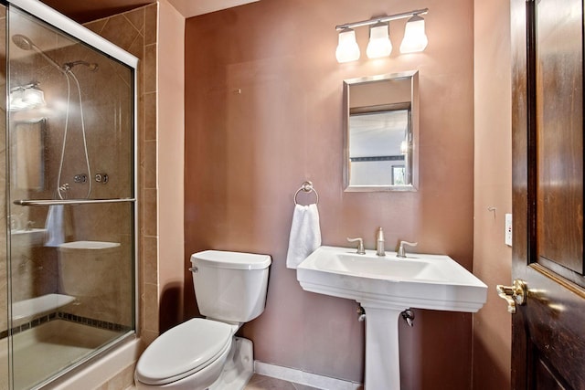 bathroom with a shower stall, toilet, and baseboards