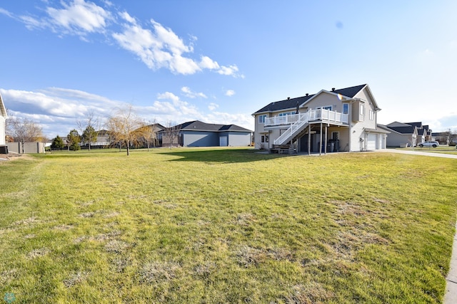 view of yard featuring a wooden deck, an attached garage, stairs, and concrete driveway