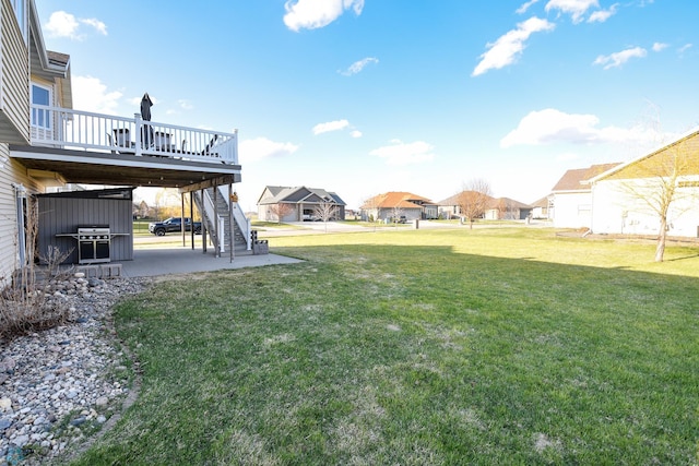 view of yard with a wooden deck, a residential view, a patio, and stairs