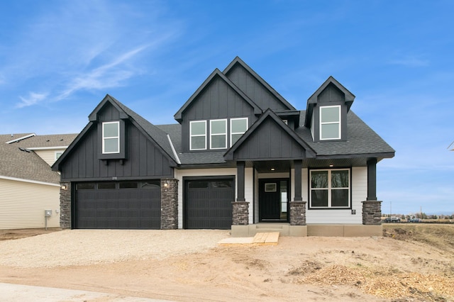 craftsman-style home with an attached garage, driveway, stone siding, and board and batten siding