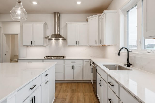 kitchen with wall chimney exhaust hood, a sink, plenty of natural light, white cabinetry, and appliances with stainless steel finishes