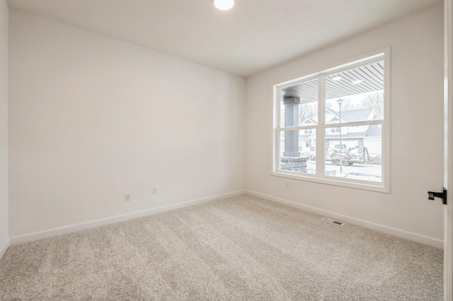 empty room featuring visible vents, baseboards, and carpet flooring
