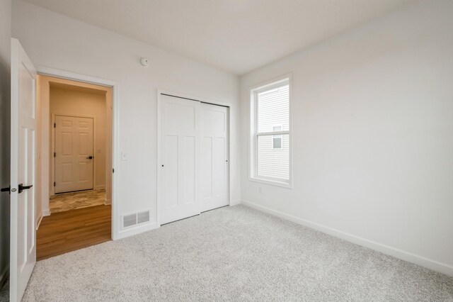 unfurnished bedroom with baseboards, visible vents, carpet, and a closet