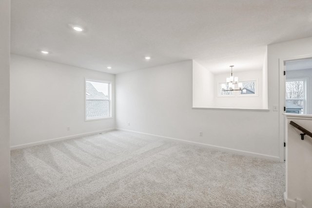 empty room with carpet floors, a chandelier, and plenty of natural light