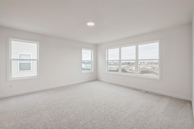 spare room featuring carpet and baseboards