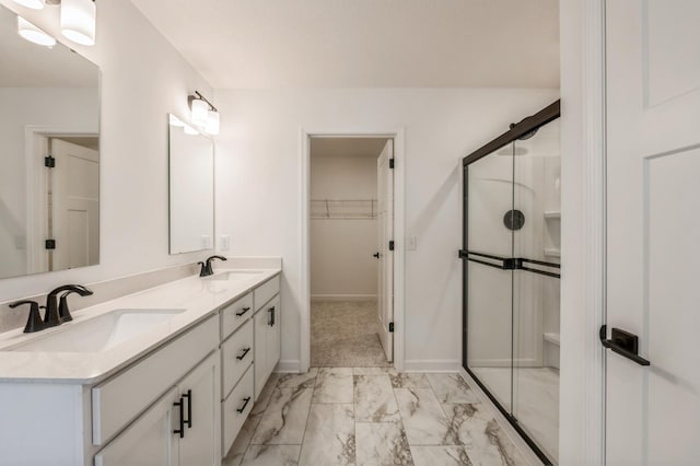bathroom featuring a walk in closet, marble finish floor, a stall shower, and a sink