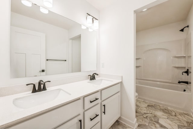 full bathroom with marble finish floor, a sink, double vanity, and toilet