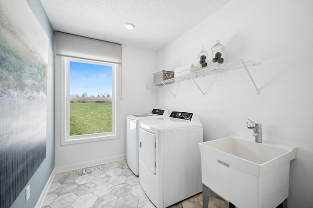 clothes washing area featuring separate washer and dryer, baseboards, visible vents, laundry area, and a sink