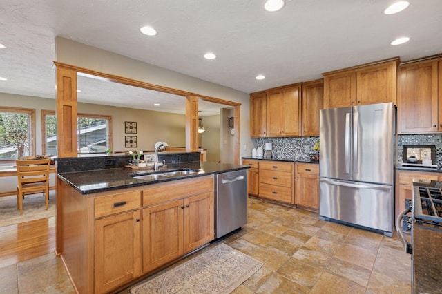 kitchen with appliances with stainless steel finishes, a sink, decorative backsplash, recessed lighting, and dark stone counters