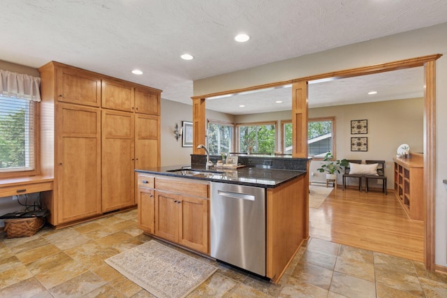 kitchen with dishwasher, a sink, dark stone countertops, recessed lighting, and a kitchen island with sink