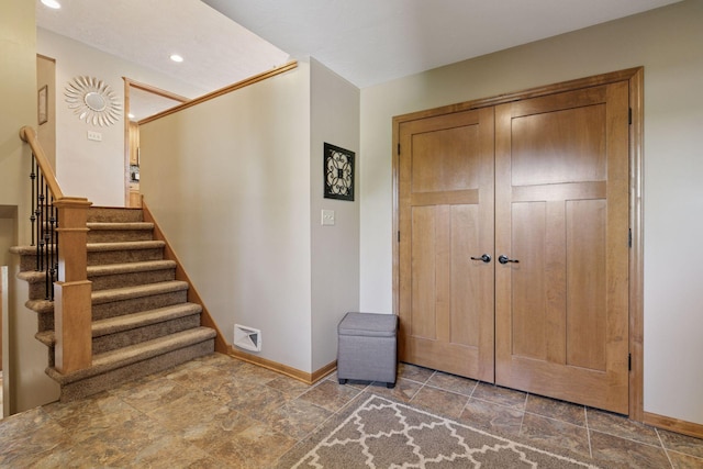 foyer featuring baseboards, stone finish floors, stairway, and recessed lighting