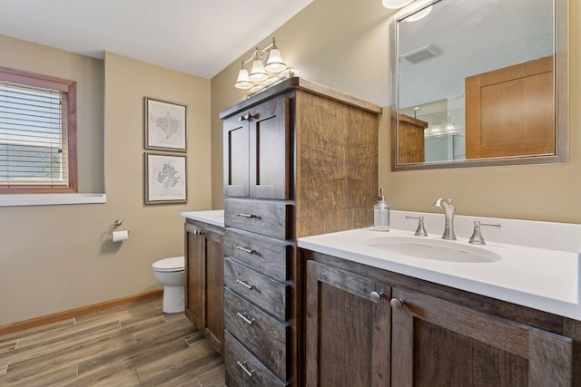 bathroom with vanity, wood finished floors, toilet, a shower, and baseboards