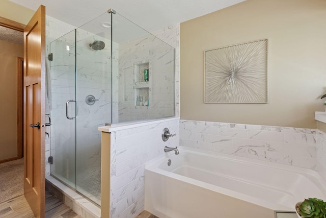 full bathroom featuring a garden tub, a shower stall, and wood finished floors