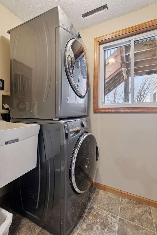 laundry area featuring stacked washing machine and dryer and baseboards